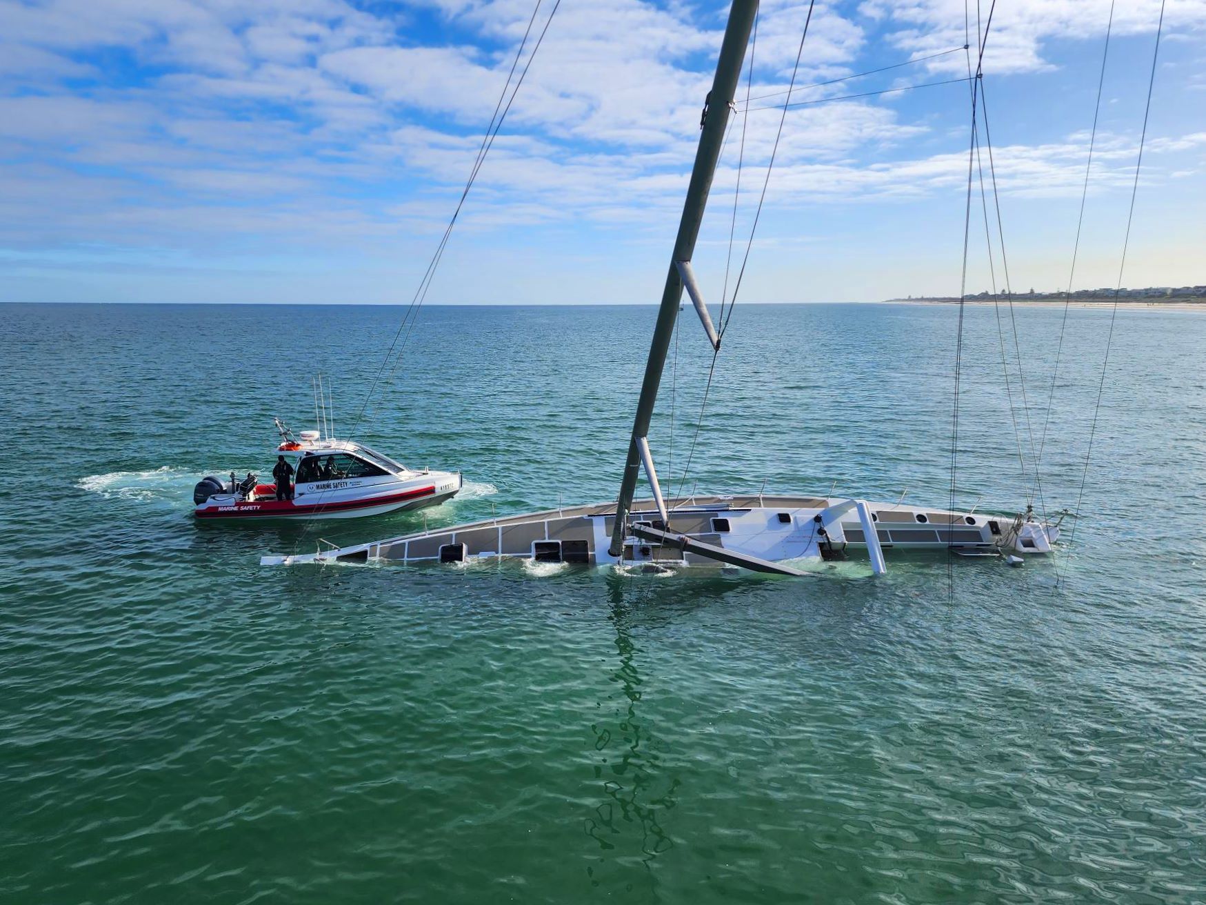 Yacht half submerged in the ocean with Marine Safety vessel close by in the water
