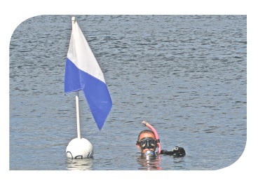 Diver in water next to diving flag