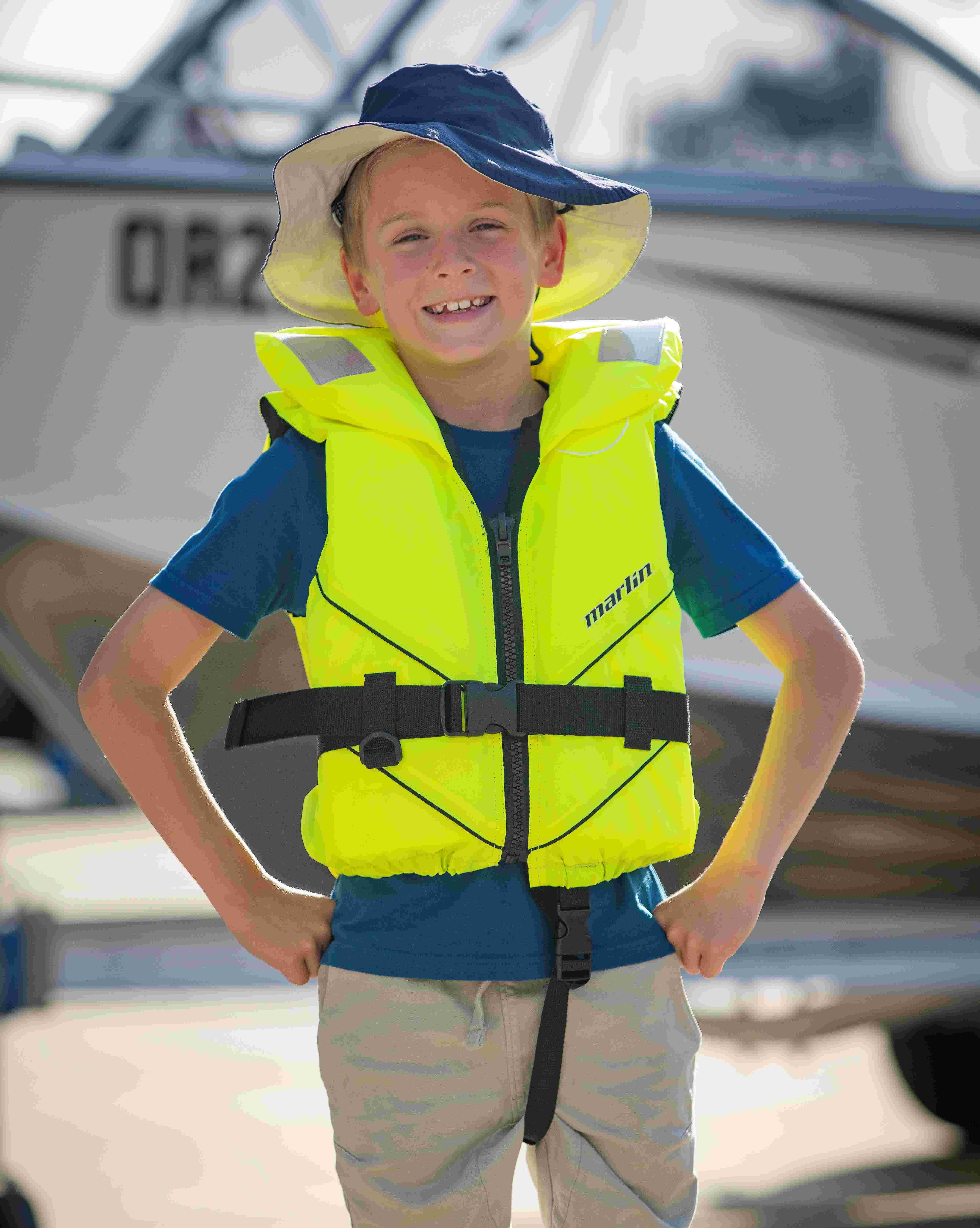 Boy standing in front of a boat with a lifejacket on