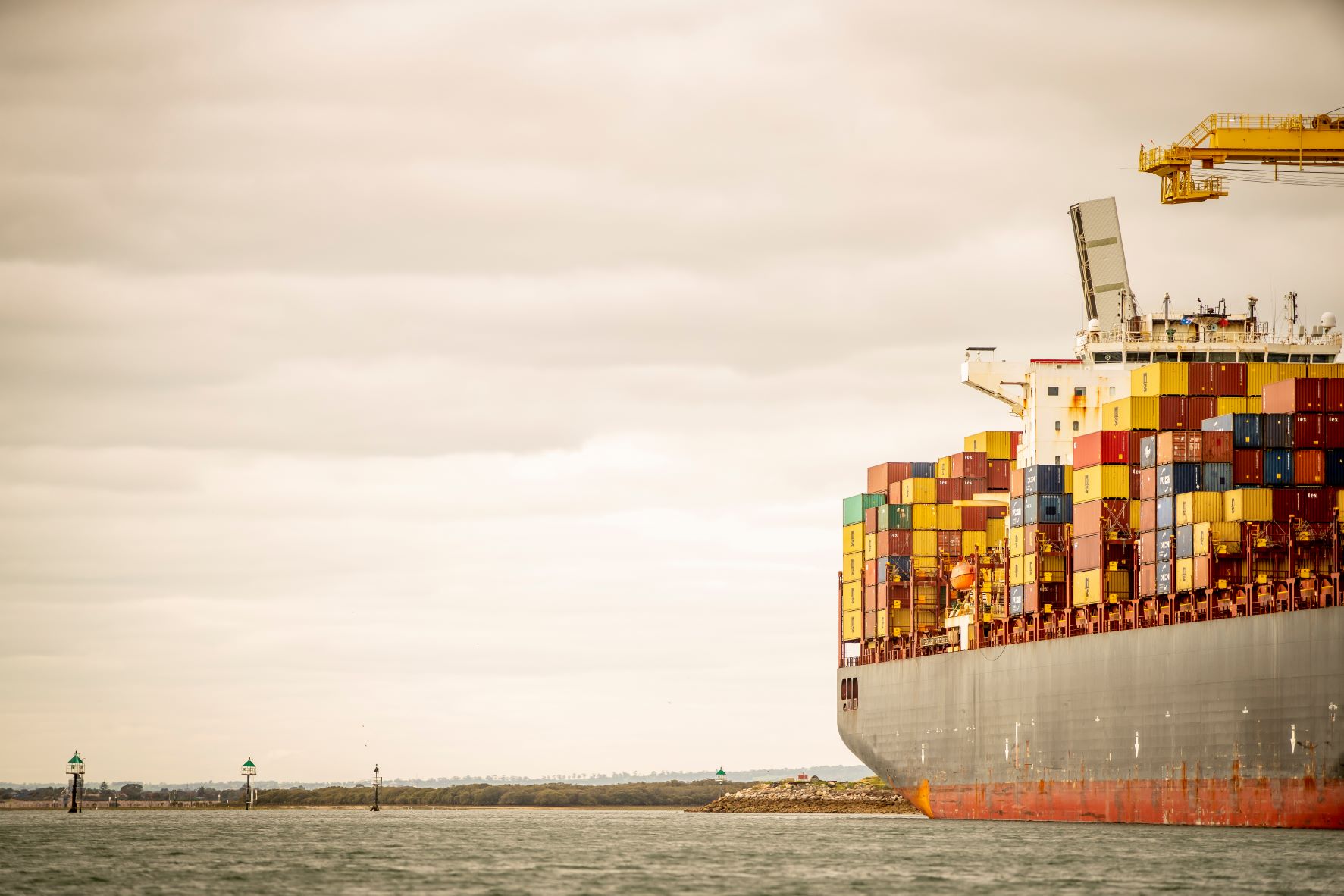 Big ship sitting on water with navigational markers in the background