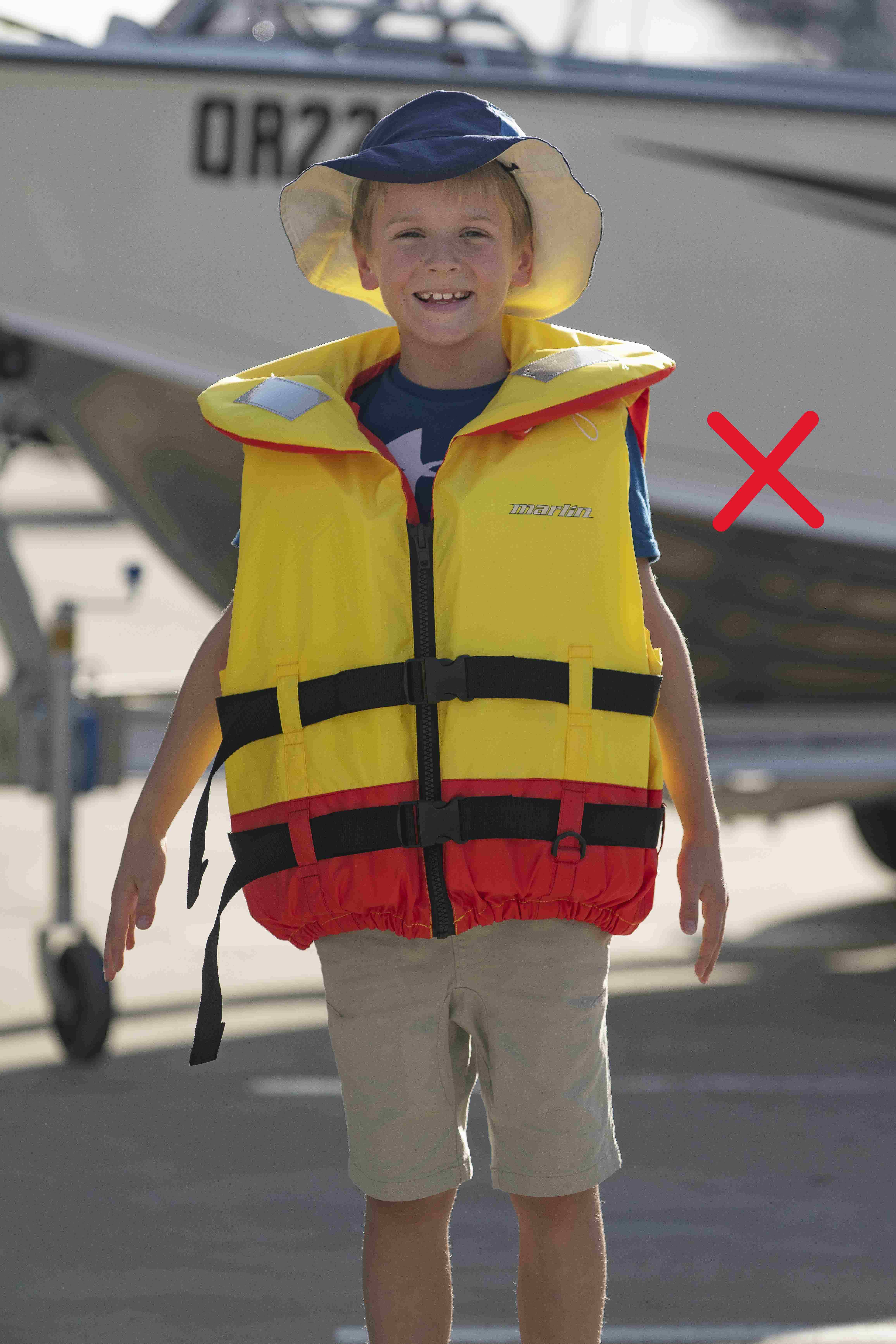 Lifejacket on a child standing up that is too big for the child