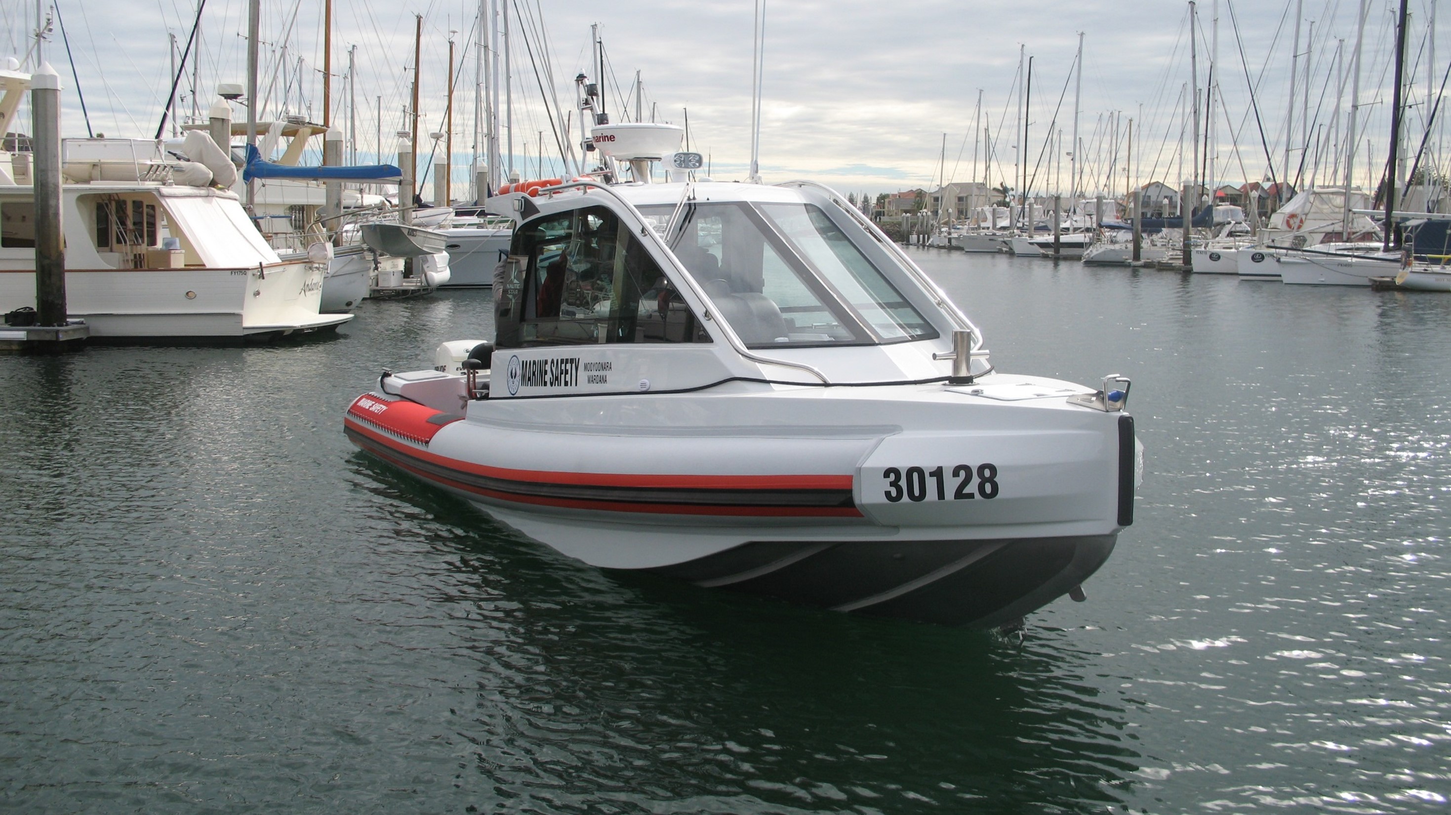 Marine Safety boat on water with boats moored behind it